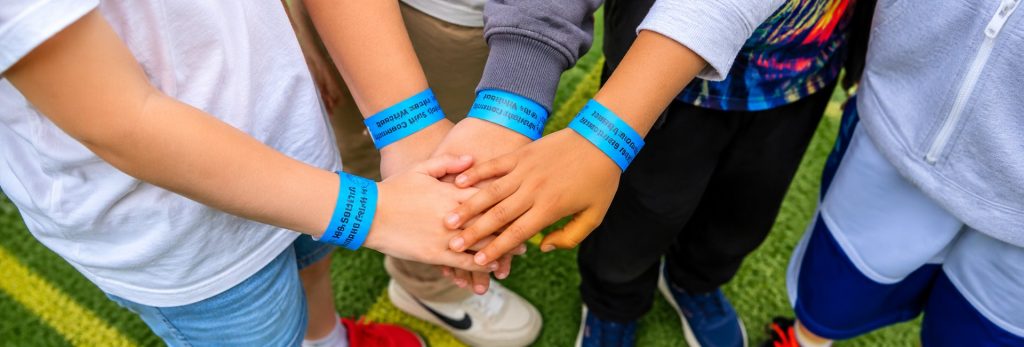 Hands wearing blue Holy Spirit Fete wristbands stacked together.